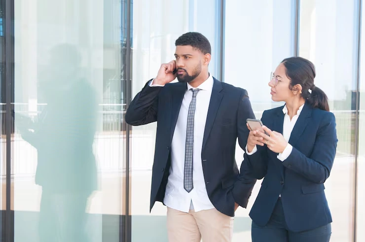 Two B2B Sales Professionals Coordinating A Cold Calling Outreach Strategy Outside A Modern Office Building