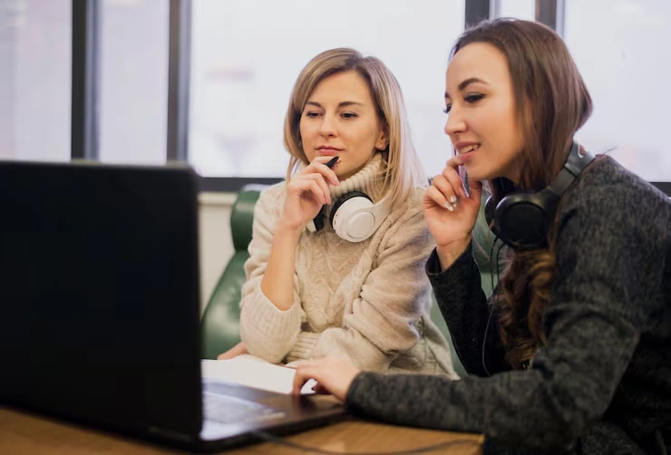 Two Professional Telemarketing Team Members With Headsets Reviewing Reporting And Insights Data On A Laptop In A Calgary Office