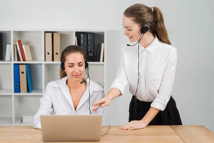 Two sales professionals collaborating on a cold calling and appointment setting process using headsets and a laptop