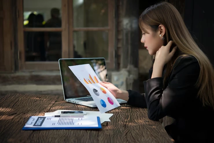 A businesswoman reviewing CRM reports and charts for cross-selling and upselling analysis