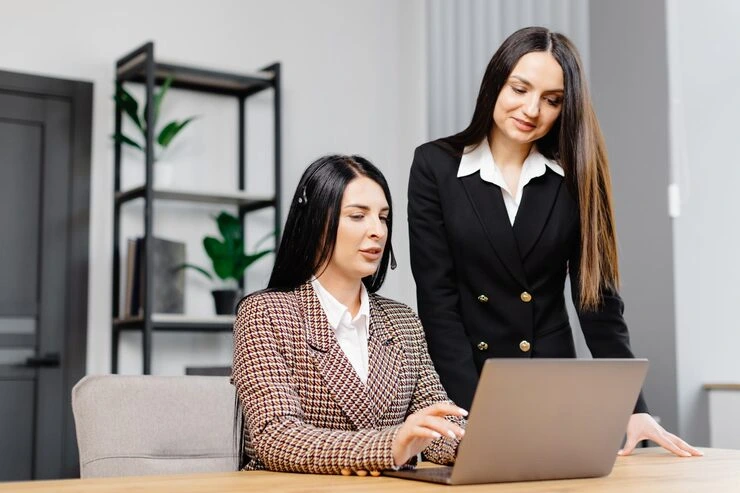 Two professional women working together on a telemarketing fundraising campaign at a laptop