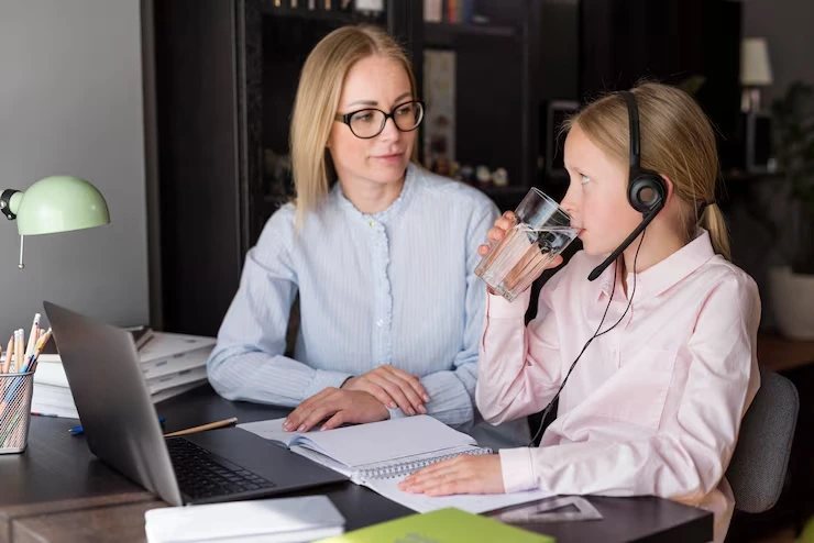 A woman supervising a young girl wearing a headset during a telemarketing session at a desk