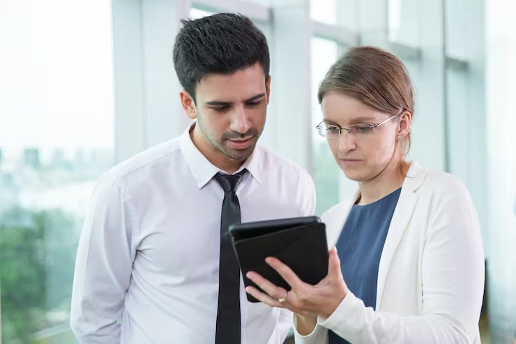 Two business professionals reviewing fundraising campaign reports on a tablet in an office